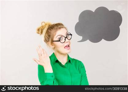 Student looking business woman wearing green shirt talking, black thinking bubble on grey background.. Woman holding black thinking bubble