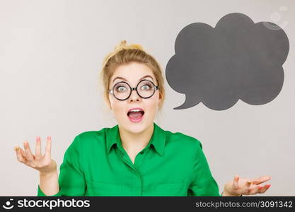 Student looking business woman wearing green shirt talking, black thinking bubble on grey background.. Woman holding black thinking bubble