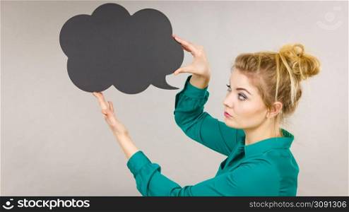Student looking business woman wearing shirt holding black thinking bubble on grey background.. Woman holding black thinking bubble