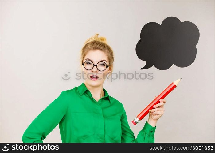 Student looking woman wearing nerdy eyeglasses holding big oversized pencil thinking about something, black speech bubble next to her. Woman holding big oversized pencil thinking