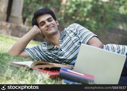 Student lying in a park with eyes closed