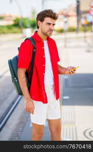 Student male waiting for a train at an outside station. Young man waiting for a train at an outside station