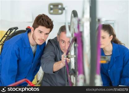 Student mechanics looking at bicycle with teacher