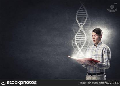 Student of biochemistry faculty. Young student guy with book in hands and DNA molecule on pages