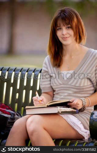 Student on bench taking notes in a journal