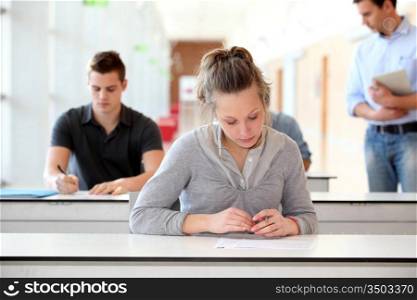 Student passing examination in school classroom