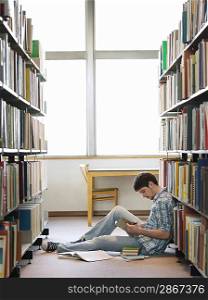 Student reading sitting on floor in library