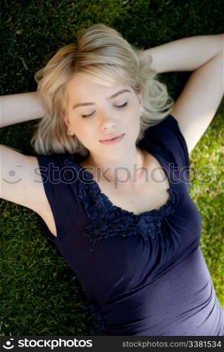 Student realxing outdoors on grass with eyes closed