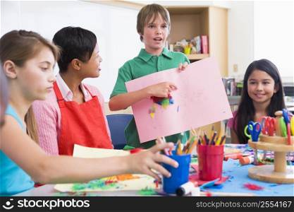 Student showing teacher and classmates his artwork (selective focus)