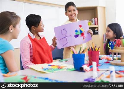 Student showing teacher and classmates his artwork (selective focus)