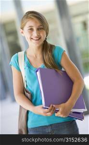 Student standing outside school with binder smiling (selective focus)