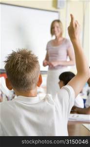 Student volunteering in class with teacher at board (selective focus)