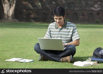 Student with a laptop sitting in a park
