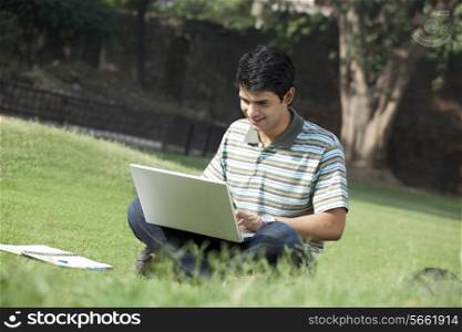 Student with a laptop sitting in a park
