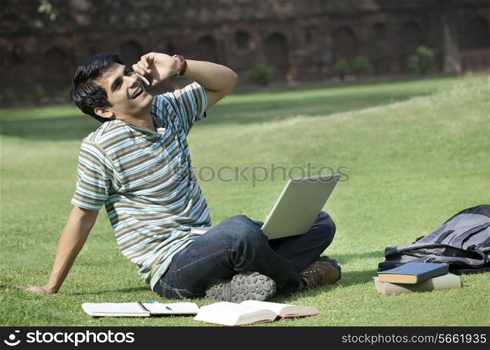 Student with a laptop talking on a mobile phone