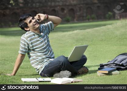Student with a laptop talking on a mobile phone