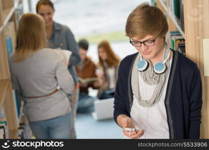 Student with headphones using mobilephone with friends in library