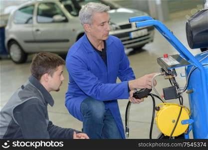student with instructor repairing a car during apprenticeship