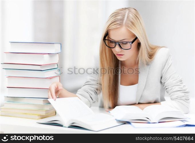 student with pile of books and notes studying indoors