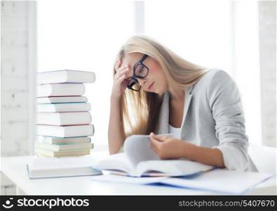 student with pile of books and notes studying indoors