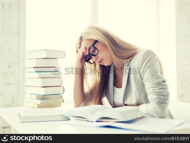 student with pile of books and notes studying indoors. student with books and notes