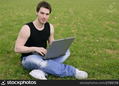student young man laptop computer on green grass meadow outdoor