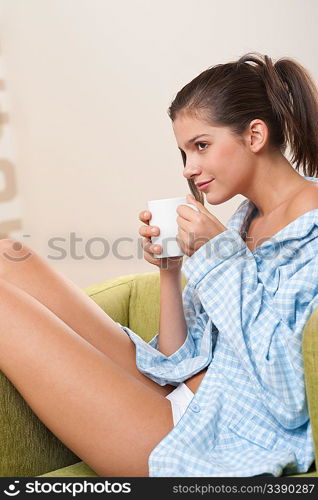 Students - Female teenager having cup of coffee, wearing pajamas in modern living room