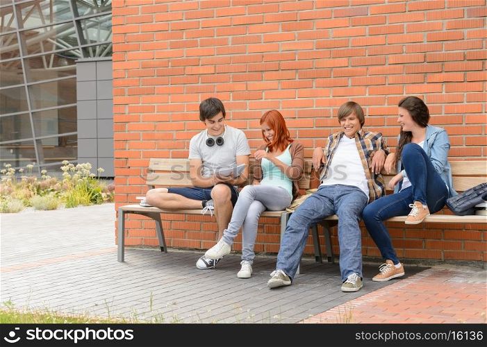 Students friends hanging out sitting on bench outside university campus