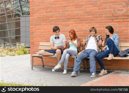 Students friends hanging out sitting on bench outside university campus