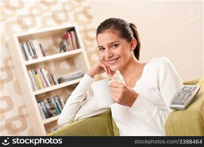 Students - Happy female teenager having drink watching television in living room