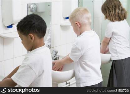 Students in bathroom at sinks washing hands