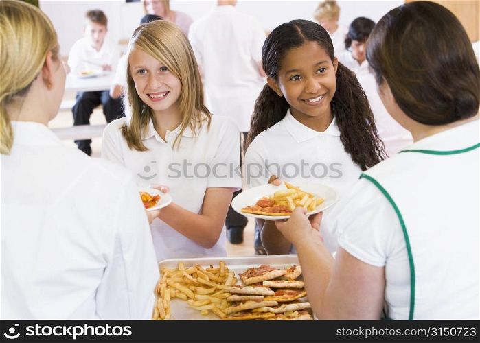 Students in cafeteria line being served by lunch ladies