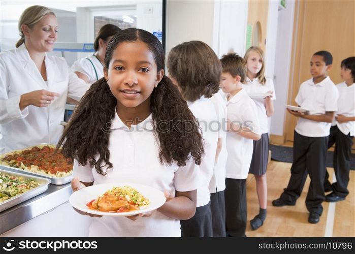 Students in cafeteria line with one holding her healthy meal and looking at camera (depth of field)