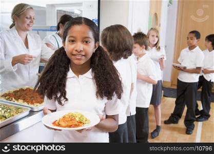 Students in cafeteria line with one holding her healthy meal and looking at camera (depth of field)