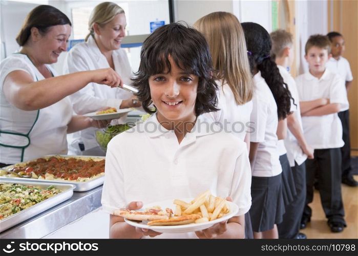 Students in cafeteria line with one holding his unhealthy meal and looking at camera (depth of field)