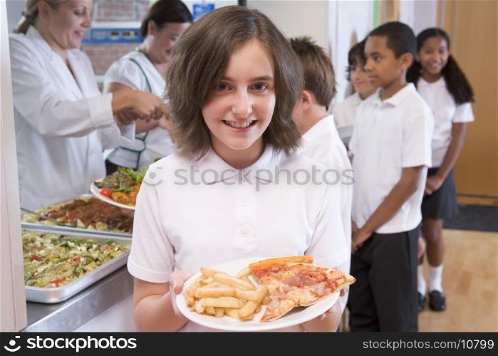 Students in cafeteria line with one holding unhealthy meal looking at camera (depth of field)