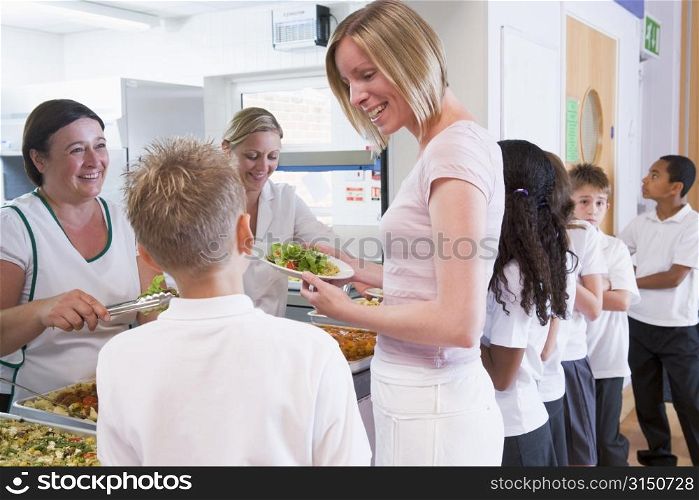 Students in cafeteria line with teacher at lunchtime
