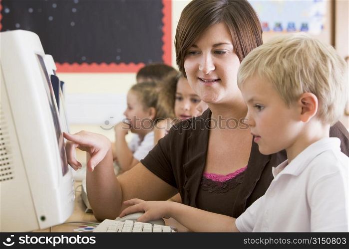 Students in class at computer terminals with teacher (selective focus)