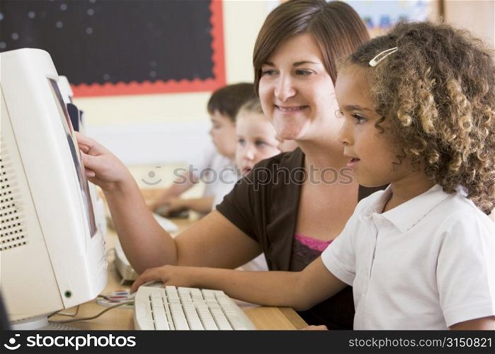 Students in class at computer terminals with teacher (selective focus)