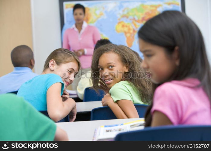 Students in class bullying student with teacher in background (selective focus)