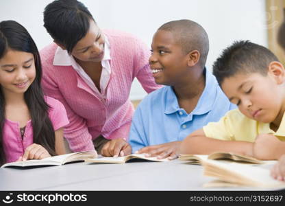 Students in class reading with teacher helping (selective focus)