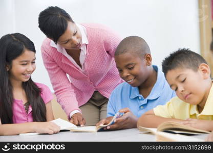 Students in class reading with teacher helping (selective focus)