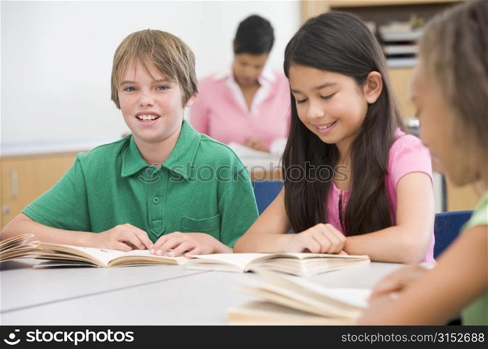 Students in class reading with teacher in background (selective focus)