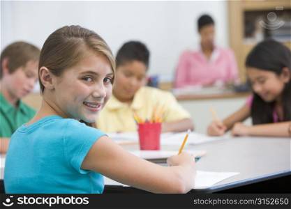 Students in class taking notes with teacher in background (selective focus)