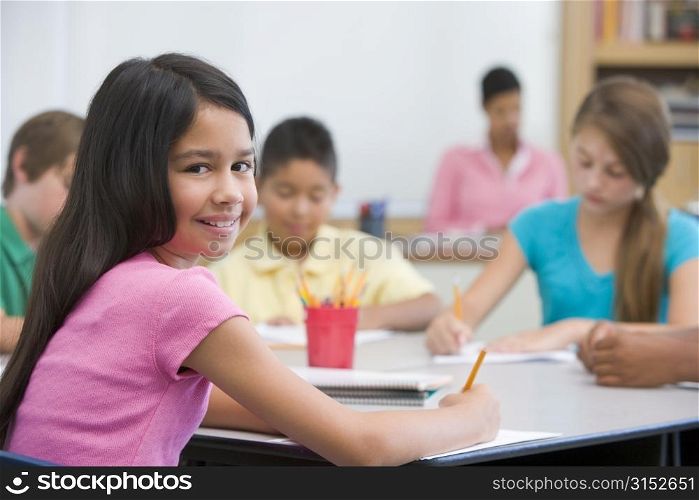Students in class taking notes with teacher in background (selective focus)