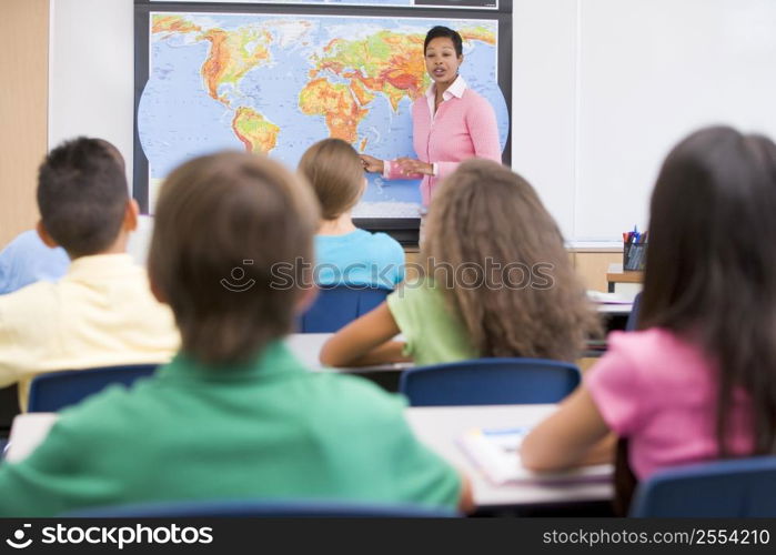 Students in class with teacher at front showing map (selective focus)