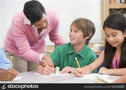 Students in class writing with teacher helping