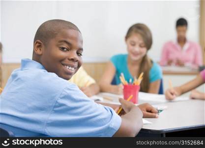 Students in class writing with teacher in background (selective focus)