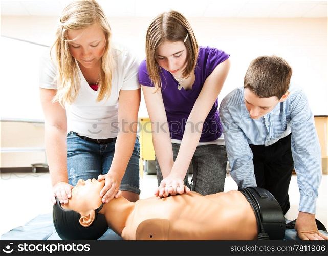 Students practicing CPR life saving techniques on a mannequin.