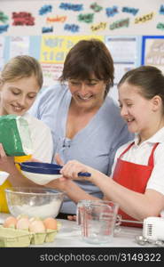 Students preparing ingredients in cooking class with teacher